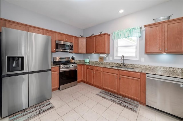 kitchen featuring stainless steel appliances, light stone countertops, sink, and light tile patterned floors