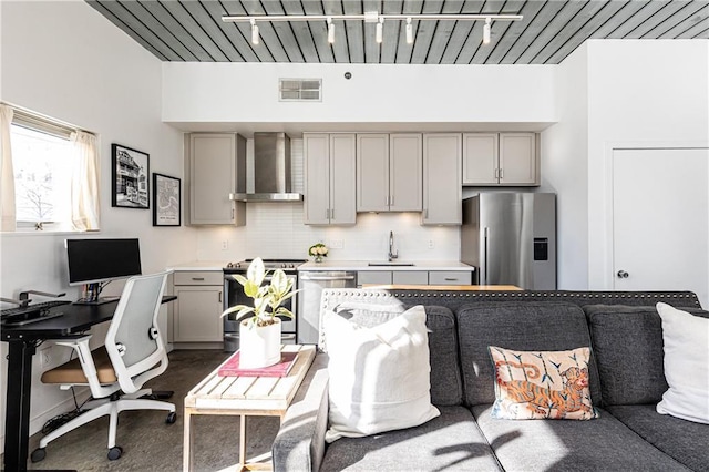 kitchen featuring visible vents, gray cabinets, appliances with stainless steel finishes, wall chimney range hood, and tasteful backsplash