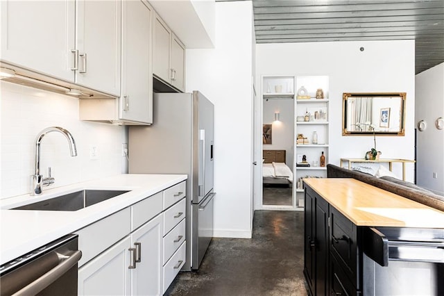 kitchen featuring a sink, decorative backsplash, stainless steel appliances, concrete flooring, and dark cabinets