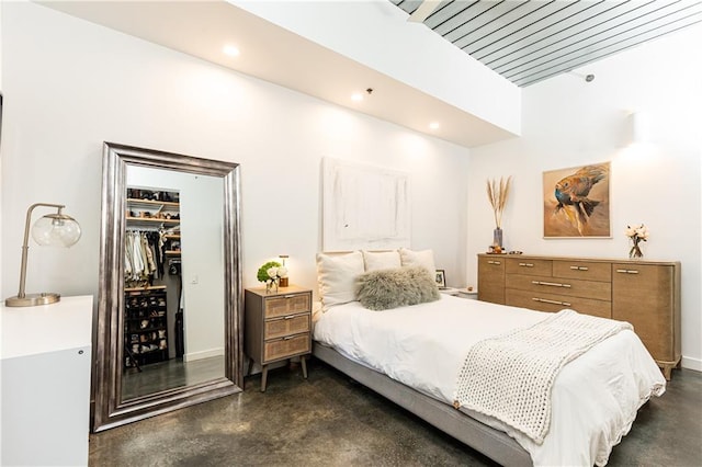 bedroom featuring recessed lighting, a closet, concrete flooring, and a spacious closet