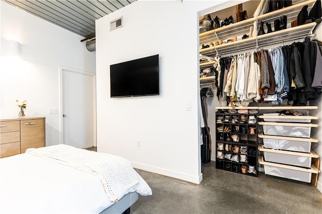 bedroom with visible vents, a walk in closet, baseboards, concrete flooring, and a closet