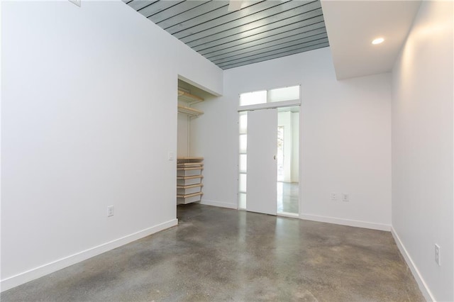 spare room featuring recessed lighting, finished concrete flooring, and baseboards