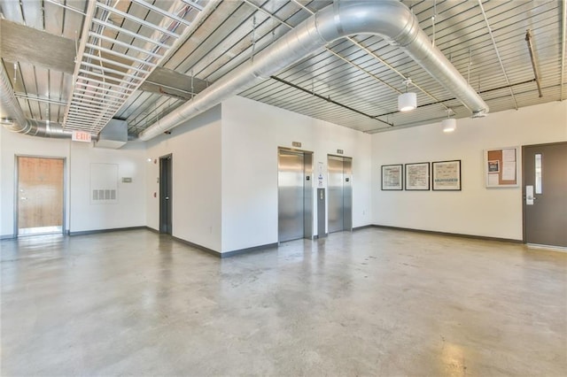 interior space featuring elevator, baseboards, and concrete flooring