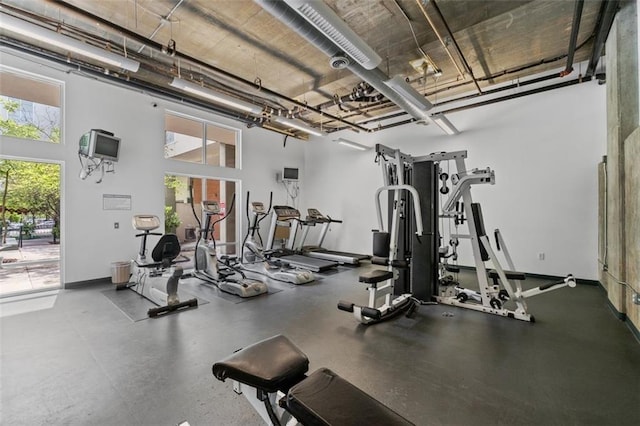 exercise room with baseboards and a towering ceiling