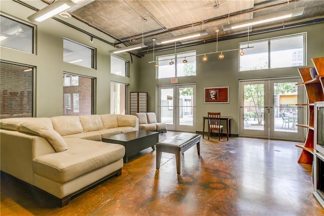 living room featuring concrete floors, french doors, and a high ceiling