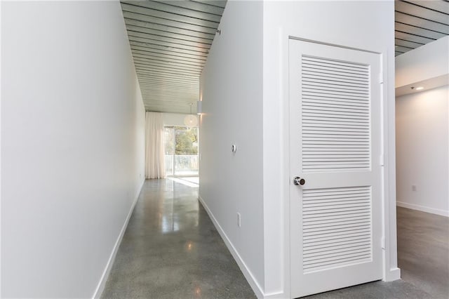 hall featuring finished concrete flooring and baseboards