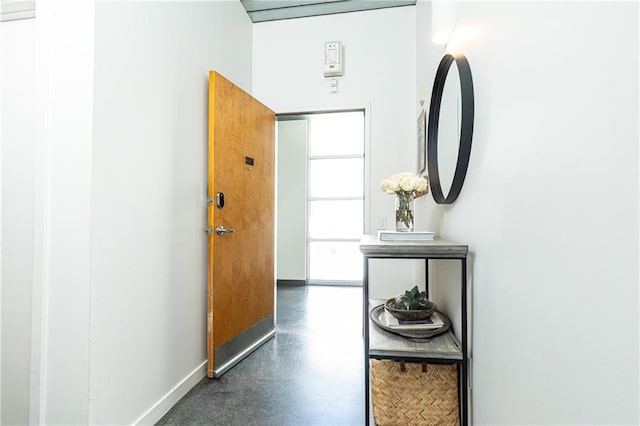 corridor with baseboards and finished concrete floors