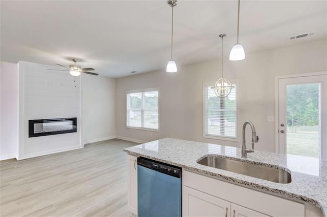 kitchen with white cabinetry, sink, hanging light fixtures, stainless steel dishwasher, and light wood-type flooring