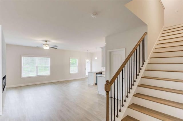 stairs with hardwood / wood-style floors and ceiling fan