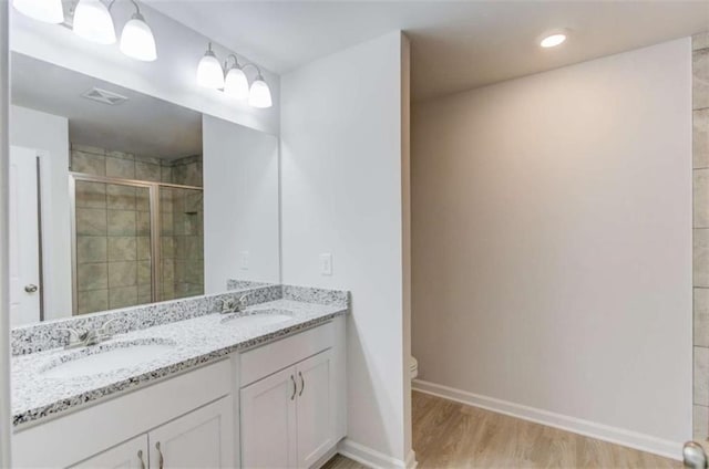 bathroom with hardwood / wood-style floors, vanity, toilet, and a shower with shower door