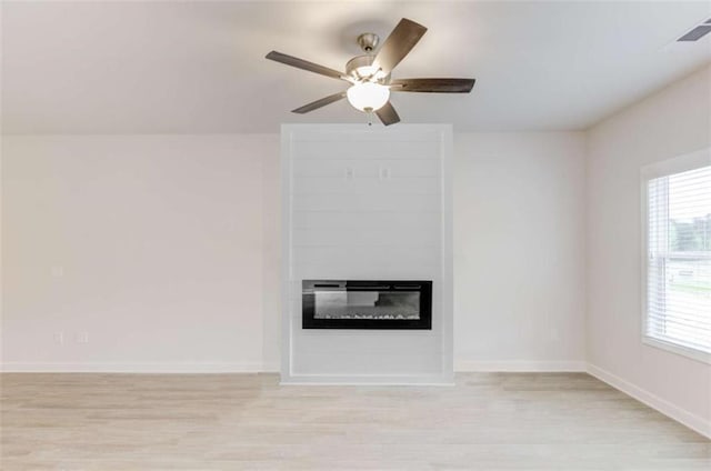 unfurnished living room featuring a fireplace, light wood-type flooring, and ceiling fan