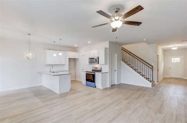 kitchen with kitchen peninsula, appliances with stainless steel finishes, pendant lighting, white cabinets, and light wood-type flooring