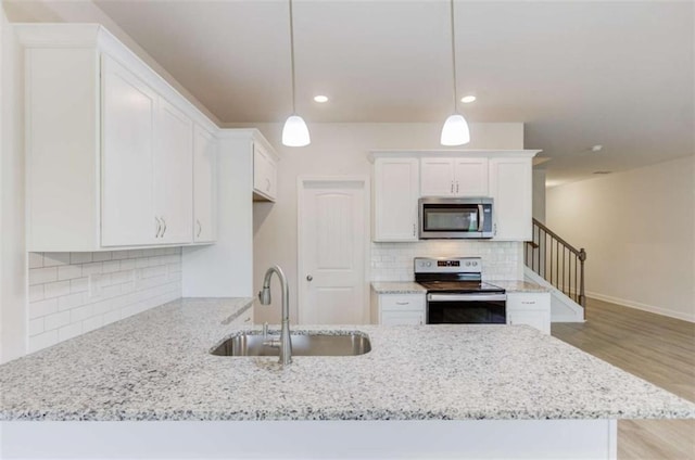 kitchen featuring decorative light fixtures, white cabinetry, sink, and appliances with stainless steel finishes