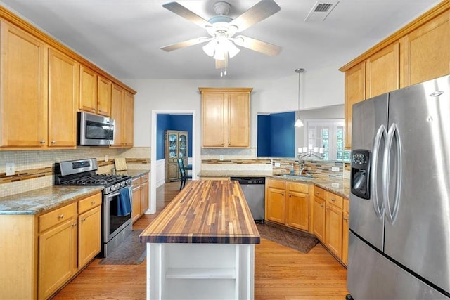 kitchen with appliances with stainless steel finishes, wooden counters, a sink, and light wood-style flooring