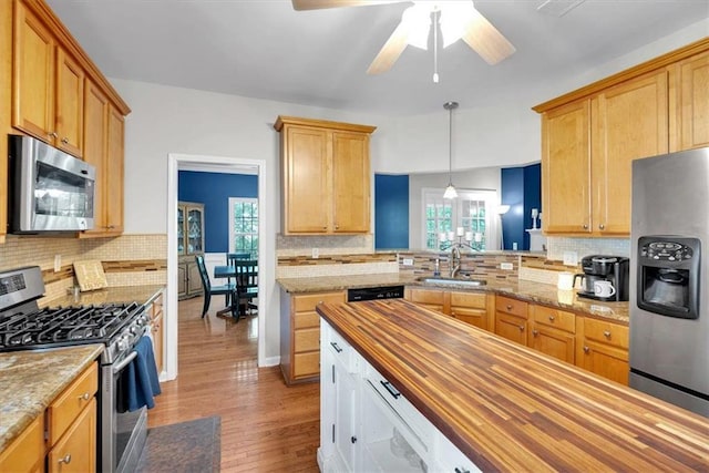 kitchen featuring stainless steel appliances, butcher block counters, a sink, and tasteful backsplash
