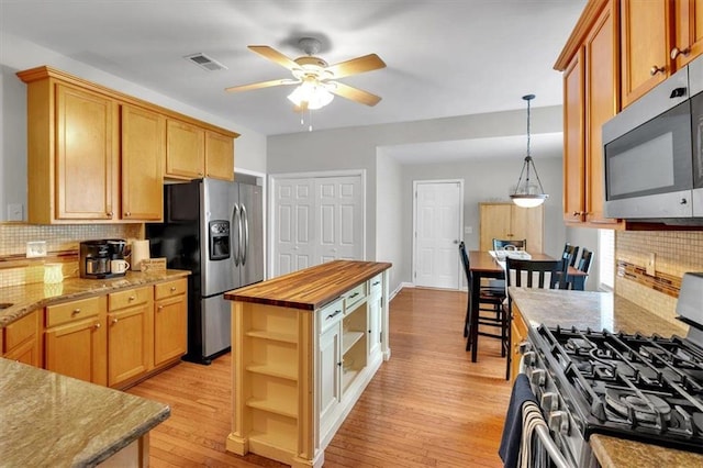 kitchen with appliances with stainless steel finishes, open shelves, ceiling fan, light wood finished floors, and backsplash