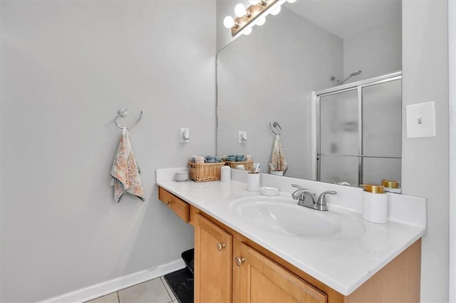 bathroom with a shower stall, tile patterned flooring, vanity, and baseboards