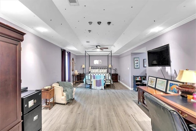living area with a tray ceiling, ceiling fan, light wood-style flooring, baseboards, and ornamental molding