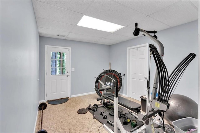 workout area featuring a paneled ceiling, carpet flooring, and baseboards