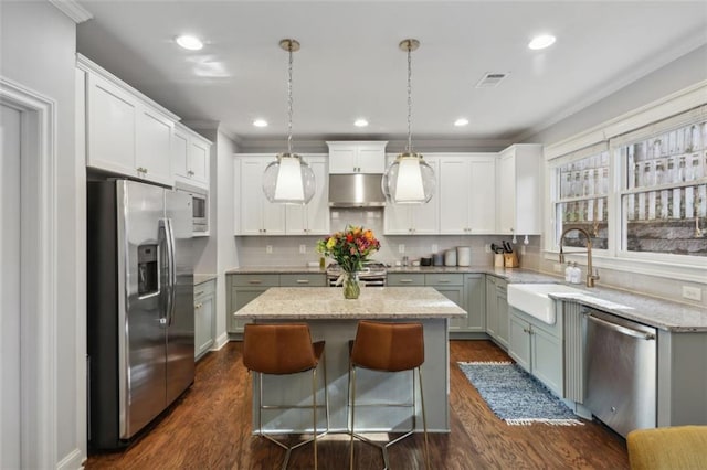 kitchen featuring stainless steel appliances, white cabinets, a center island, hanging light fixtures, and dark hardwood / wood-style floors