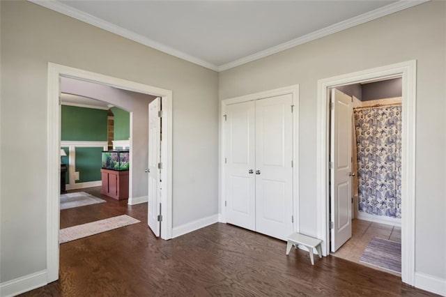 unfurnished bedroom featuring ensuite bathroom, a closet, crown molding, and dark hardwood / wood-style floors