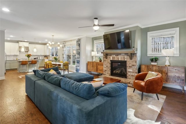 living room featuring ceiling fan with notable chandelier, a fireplace, ornamental molding, and hardwood / wood-style floors