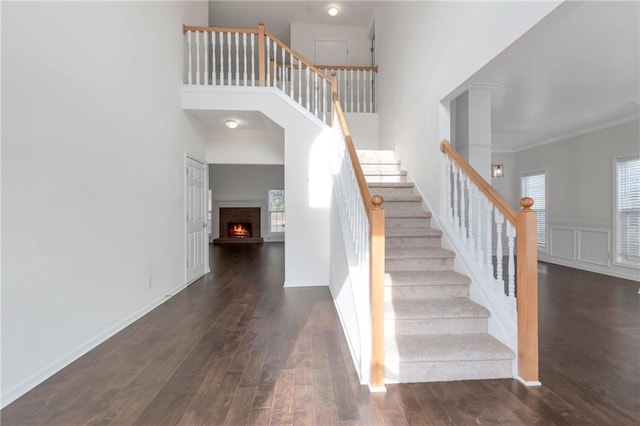 staircase with hardwood / wood-style floors, crown molding, and a high ceiling