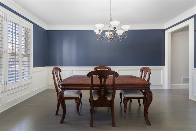 dining area with dark wood-type flooring, ornamental molding, and a chandelier