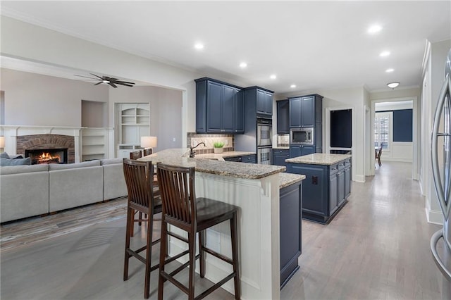 kitchen featuring blue cabinetry, appliances with stainless steel finishes, a kitchen breakfast bar, kitchen peninsula, and a kitchen island