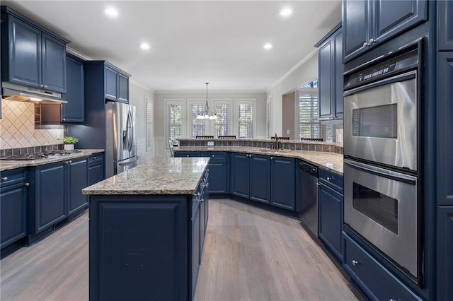 kitchen featuring blue cabinets, appliances with stainless steel finishes, a center island, and hanging light fixtures