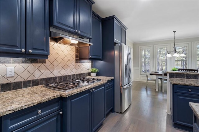 kitchen featuring dark wood-type flooring, blue cabinets, light stone counters, hanging light fixtures, and appliances with stainless steel finishes