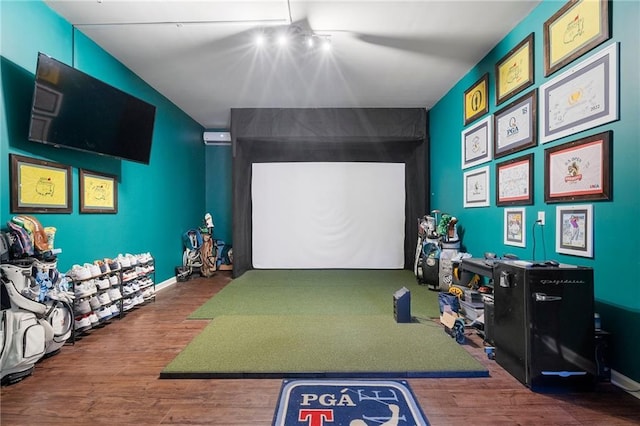 recreation room with golf simulator, rail lighting, and hardwood / wood-style floors