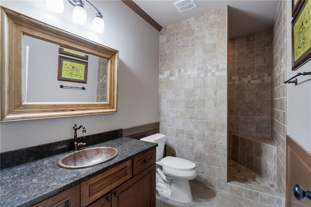 bathroom with tiled shower, tile patterned floors, toilet, vanity, and ornamental molding