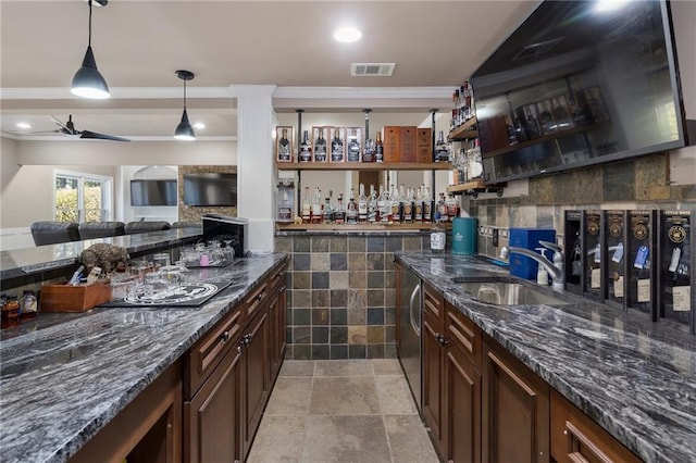 bar featuring dark stone countertops, hanging light fixtures, dark brown cabinets, and sink