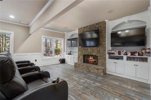 living room with hardwood / wood-style floors, crown molding, and a stone fireplace