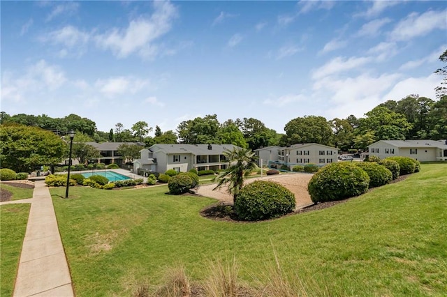 view of grassy yard featuring a residential view and an outdoor pool