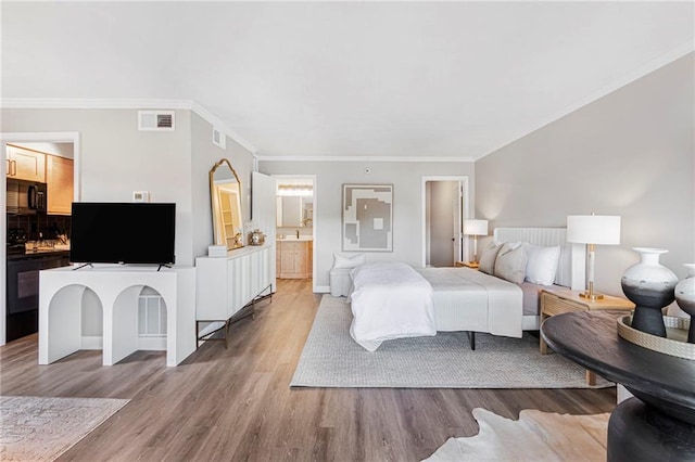 bedroom with wood finished floors, crown molding, baseboards, and connected bathroom