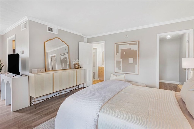 bedroom with wood finished floors, ornamental molding, baseboards, and a spacious closet