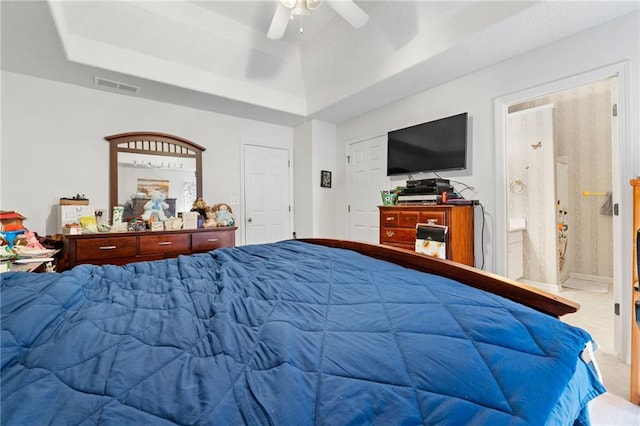 bedroom featuring carpet flooring, a tray ceiling, ceiling fan, and ensuite bathroom