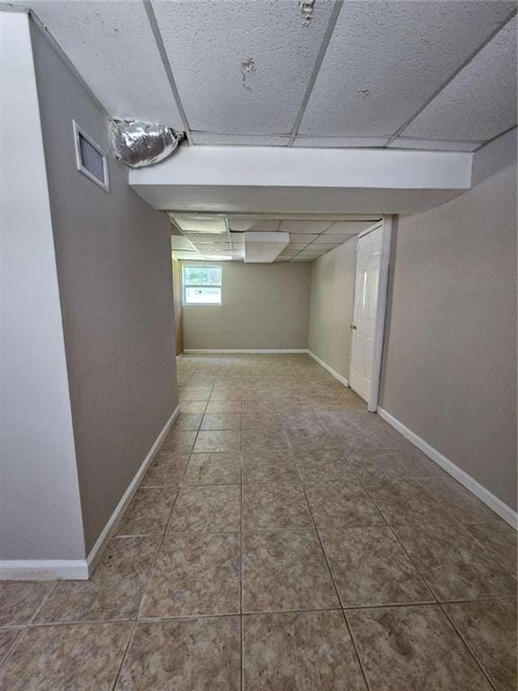 basement featuring tile patterned flooring and a paneled ceiling