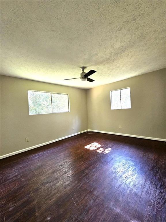 spare room with ceiling fan, dark hardwood / wood-style flooring, and plenty of natural light