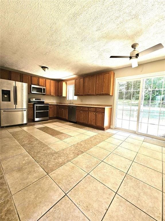 kitchen with light tile patterned floors, appliances with stainless steel finishes, a healthy amount of sunlight, and ceiling fan