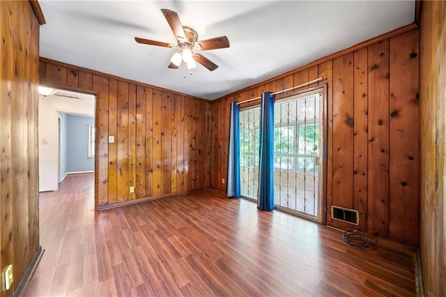 spare room with hardwood / wood-style flooring, wooden walls, and ceiling fan