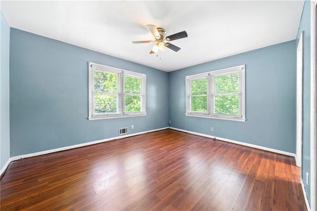 empty room with dark hardwood / wood-style flooring, a wealth of natural light, and ceiling fan