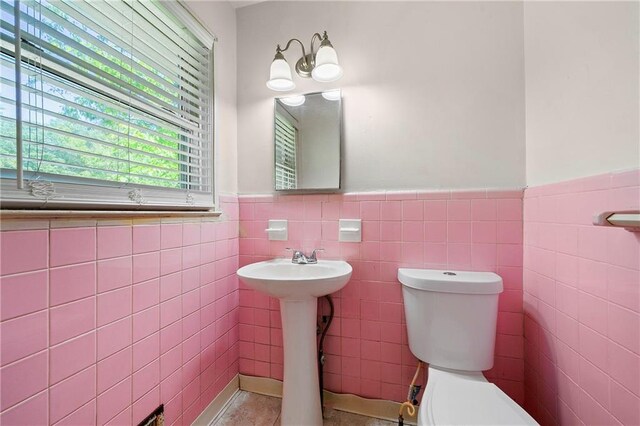 bathroom featuring tile walls, sink, and toilet