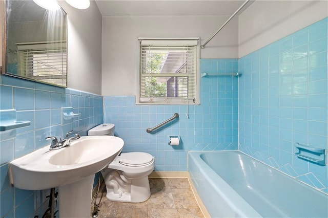 bathroom featuring tiled shower / bath, toilet, and tile walls