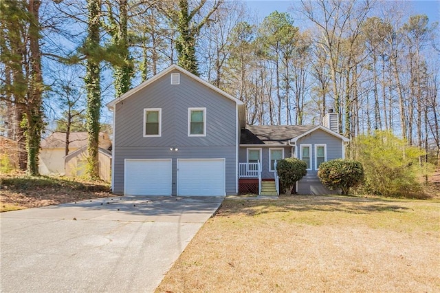 split level home with a chimney, an attached garage, concrete driveway, and a front lawn