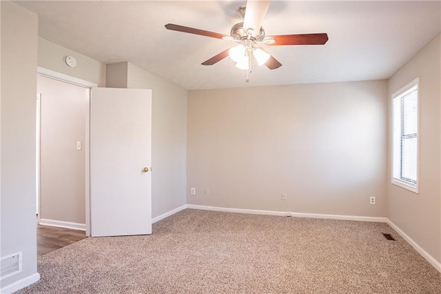 unfurnished room featuring visible vents, carpet floors, baseboards, and a ceiling fan