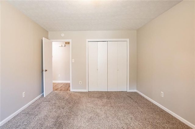 unfurnished bedroom with a closet, carpet flooring, a textured ceiling, and baseboards