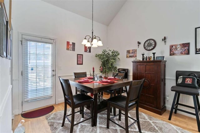 dining room featuring high vaulted ceiling, a notable chandelier, and light wood-type flooring